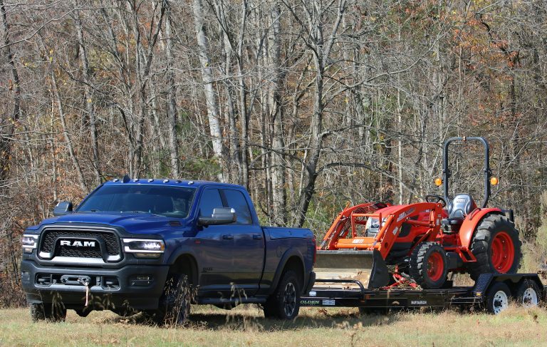 A Ram is towing a small farm tractor showcasing it's power