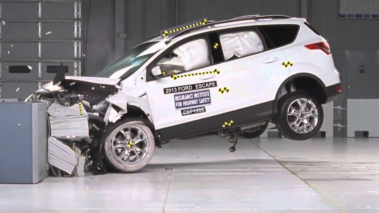 2013 Ford Escape undergoes a frontal crash test, showing severe front-end damage and deployed airbags