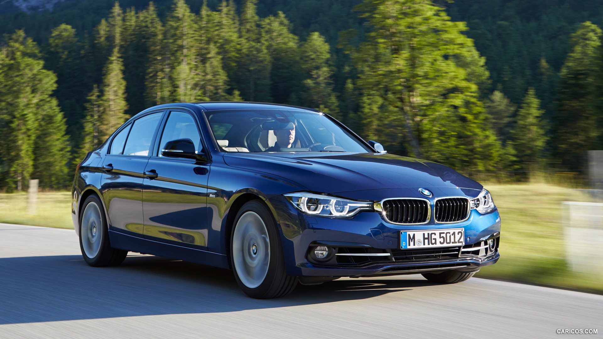 2016 BMW 3 Series sedan cruising along a forest-lined road, highlighting its sporty design