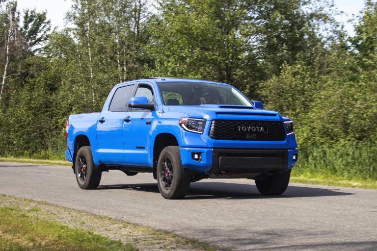 A blue Toyota Tundra is standing on a rubble in a forest