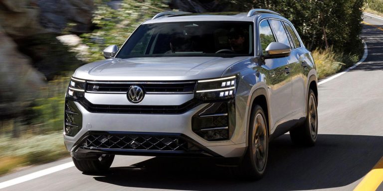 2027 Volkswagen Atlas SUV driving on a winding road, showcasing its bold front grille and modern LED headlights