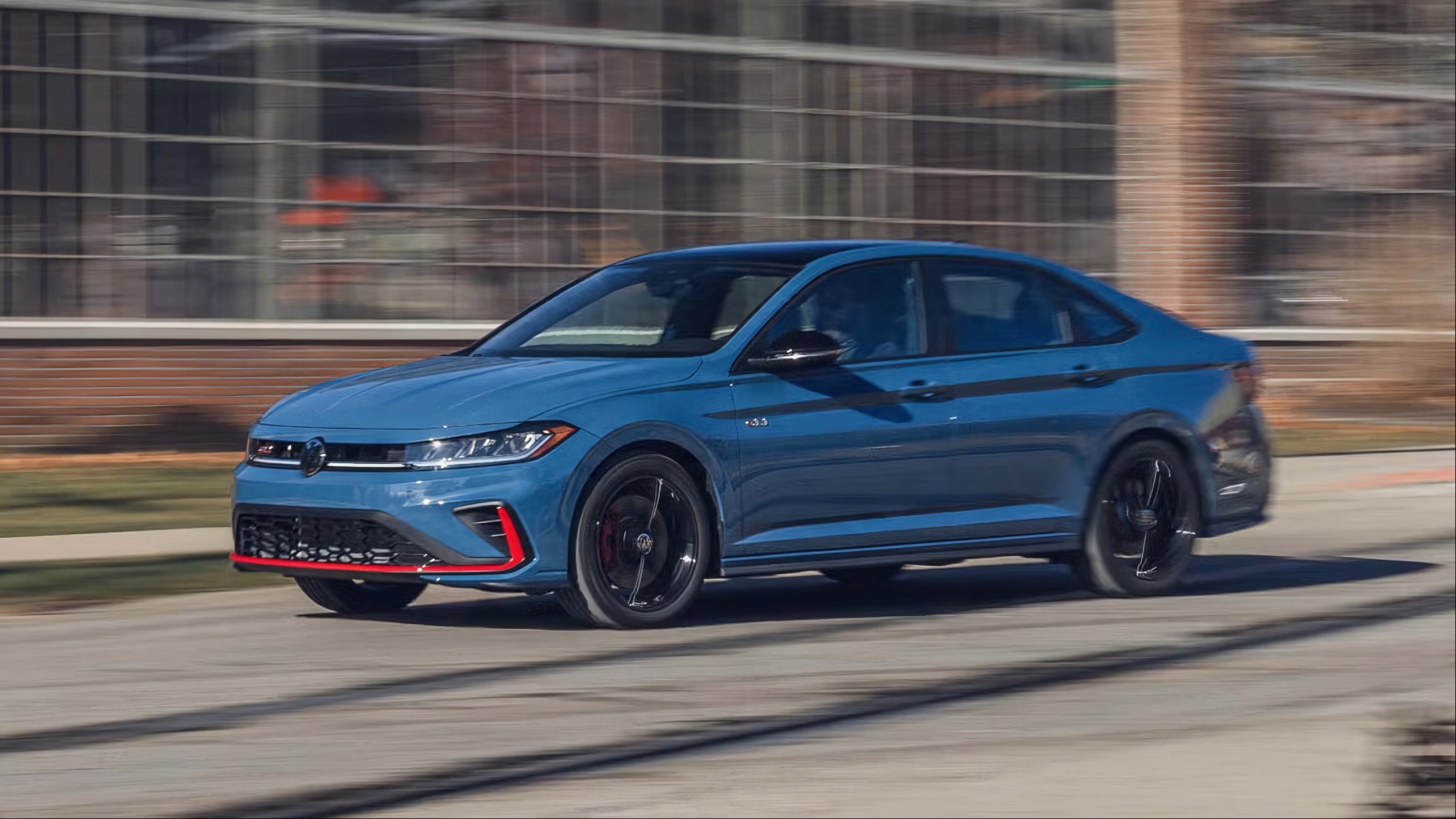Blue Volkswagen Jetta sedan speeds down city road with blur