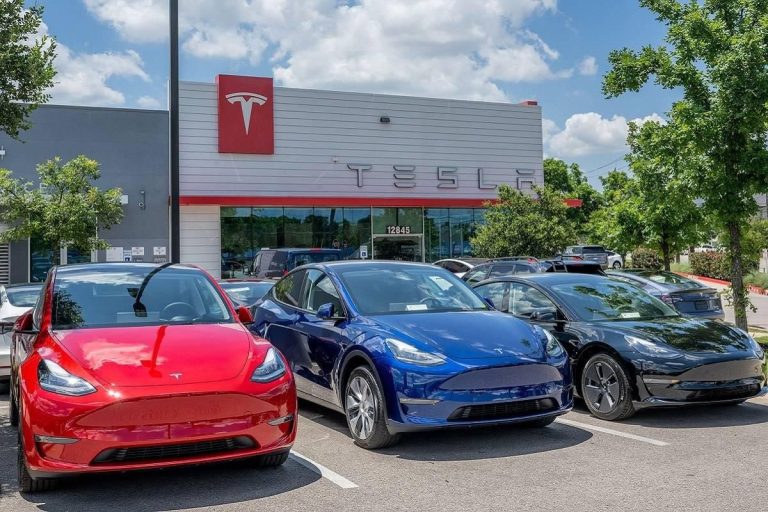 Tesla vehicles parked outside a Tesla dealership showroom