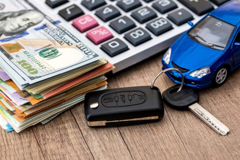 Car key, calculator, and stacks of cash illustrating rising vehicle ownership costs, monthly payments, and car affordability challenges