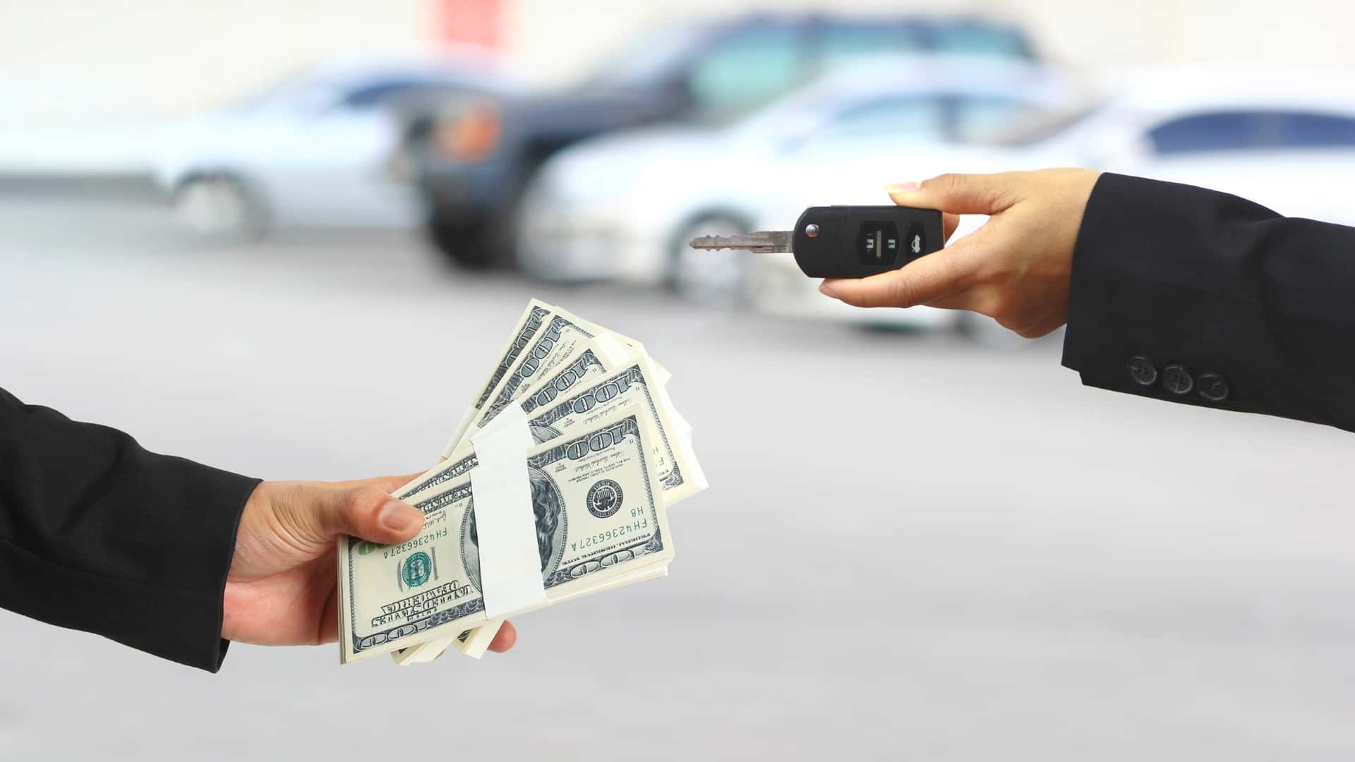A car buyer exchanges cash for vehicle keys, illustrating an automotive purchase or financing transaction