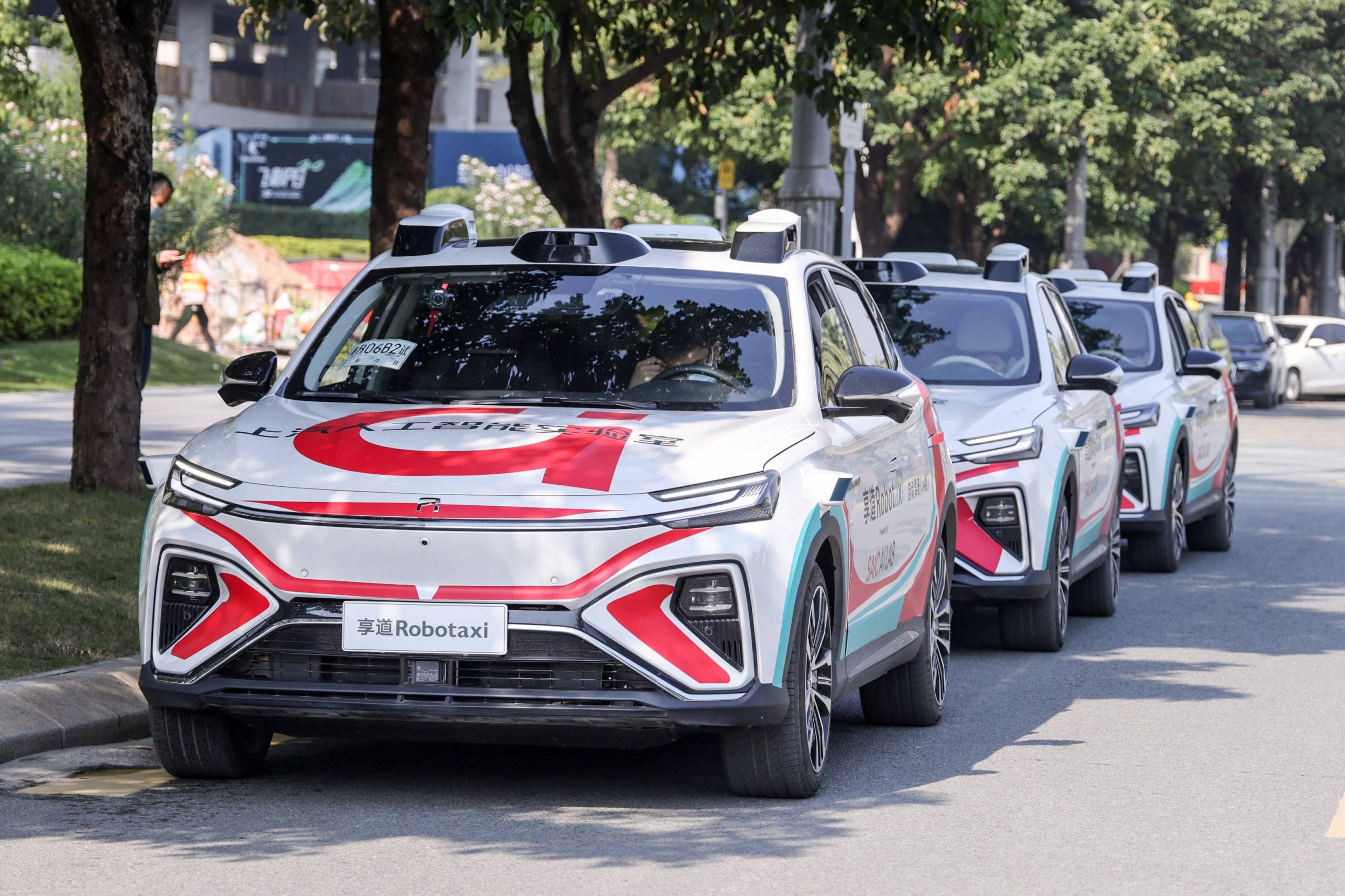 A lineup of autonomous robotaxis parked along an urban street, showcasing self-driving technology