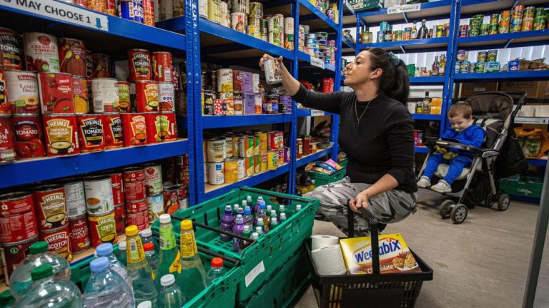 A shopper selects canned groceries from a well-stocked supermarket aisle