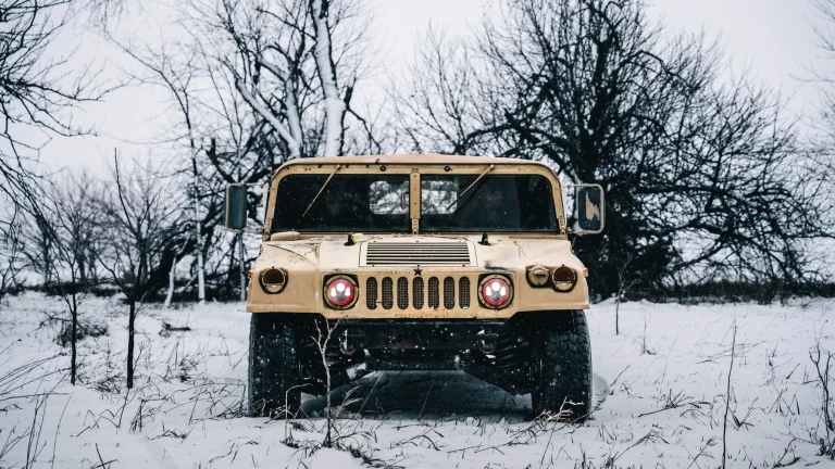 An Army Hummer is standing in a snowy road