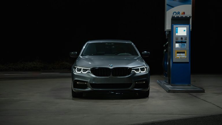 A BMW series is standing on a gas station at night
