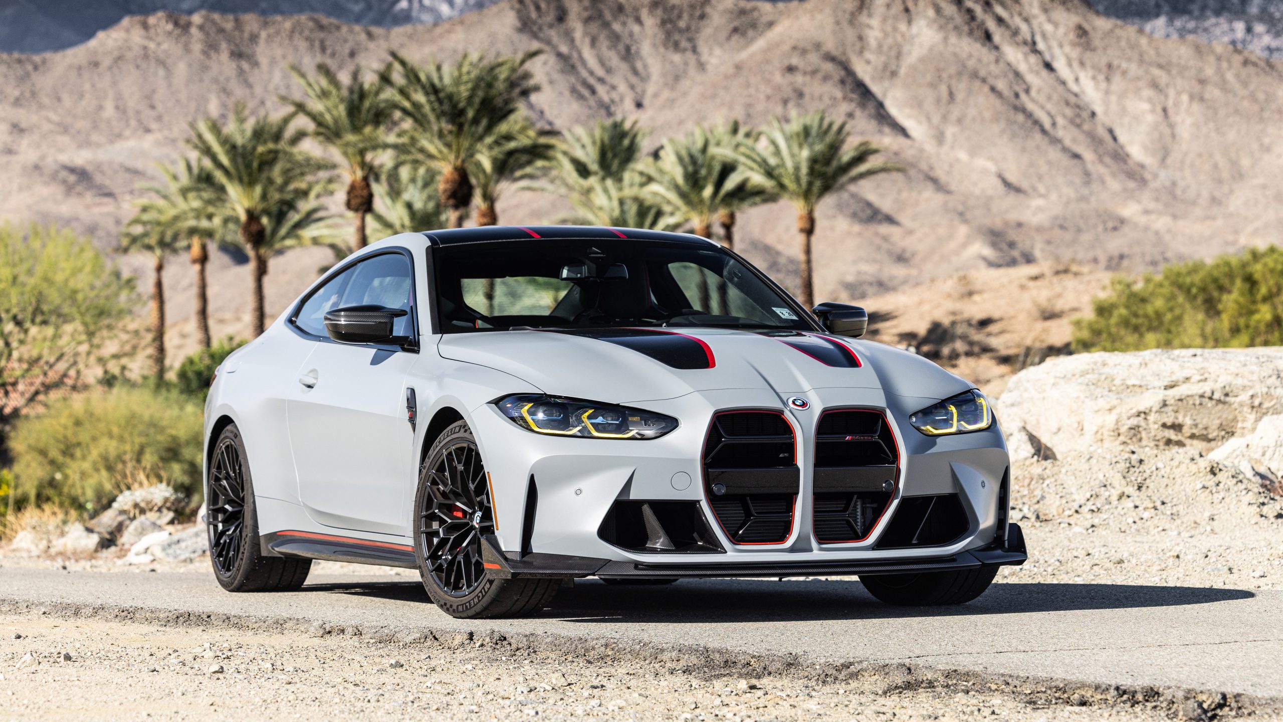 BMW M4 CSL parked on a desert road, featuring aggressive styling, red accents, and black alloy wheels
