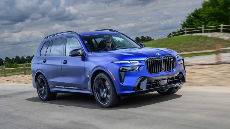 BMW SUV drives along a scenic road with rolling countryside and dramatic clouds