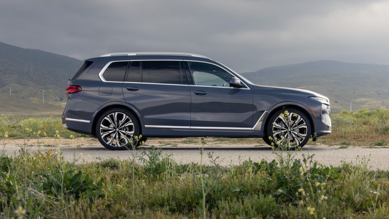 BMW X7 parked beside open grassland, with rolling hills stretching across the background