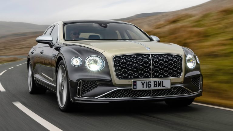 Bentley Flying Spur speeding along a scenic mountain road, showcasing elegant luxury and performance