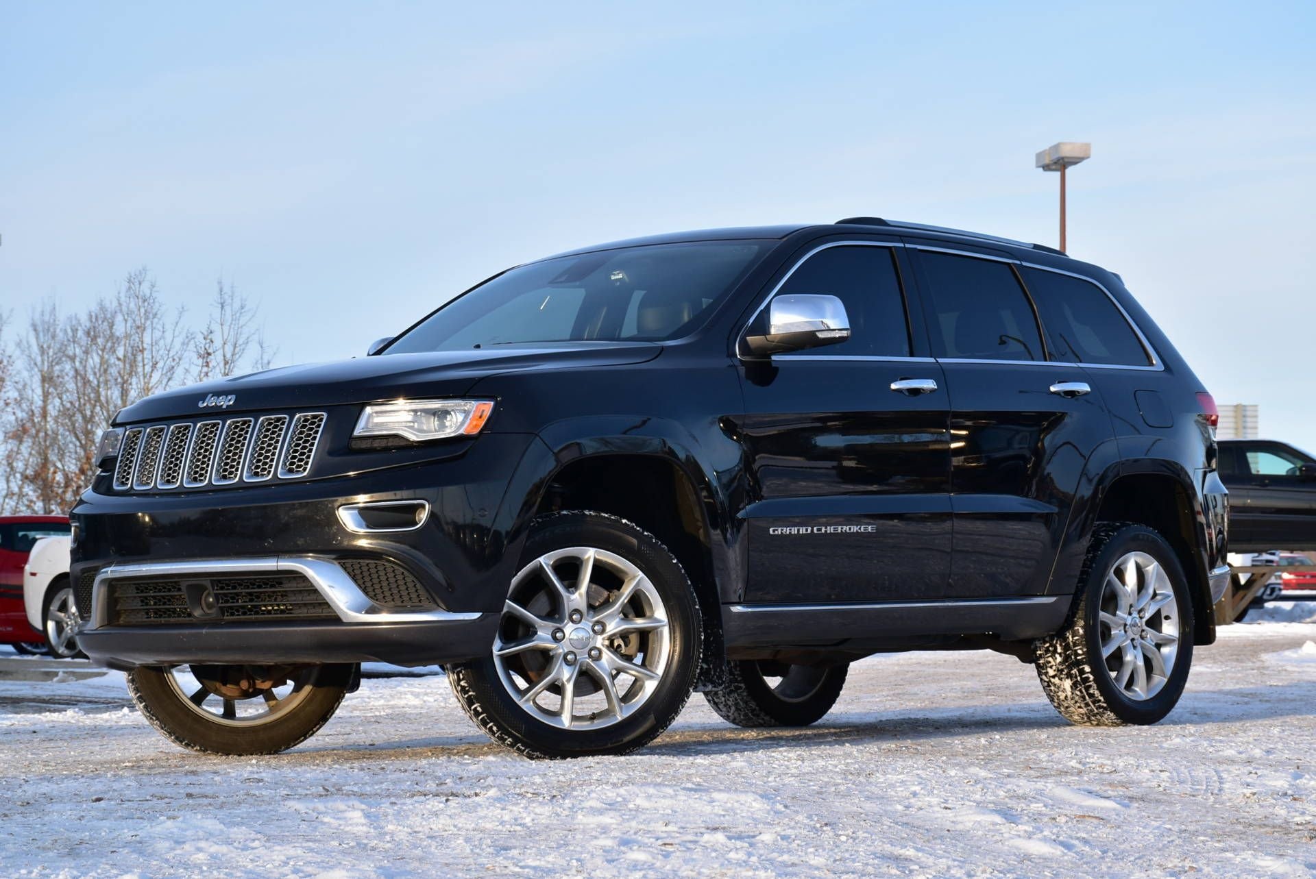 Black Jeep Grand Cherokee parked on snowy pavement, showcasing its rugged design and chrome accents