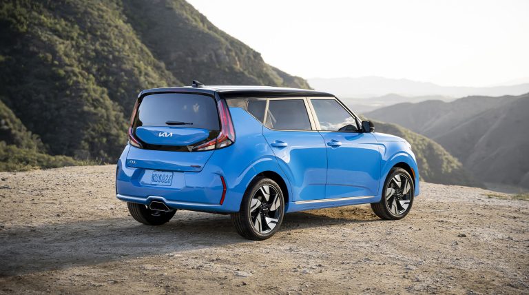 Blue Kia Soul parked on a scenic mountain overlook, showcasing its distinctive hatchback design