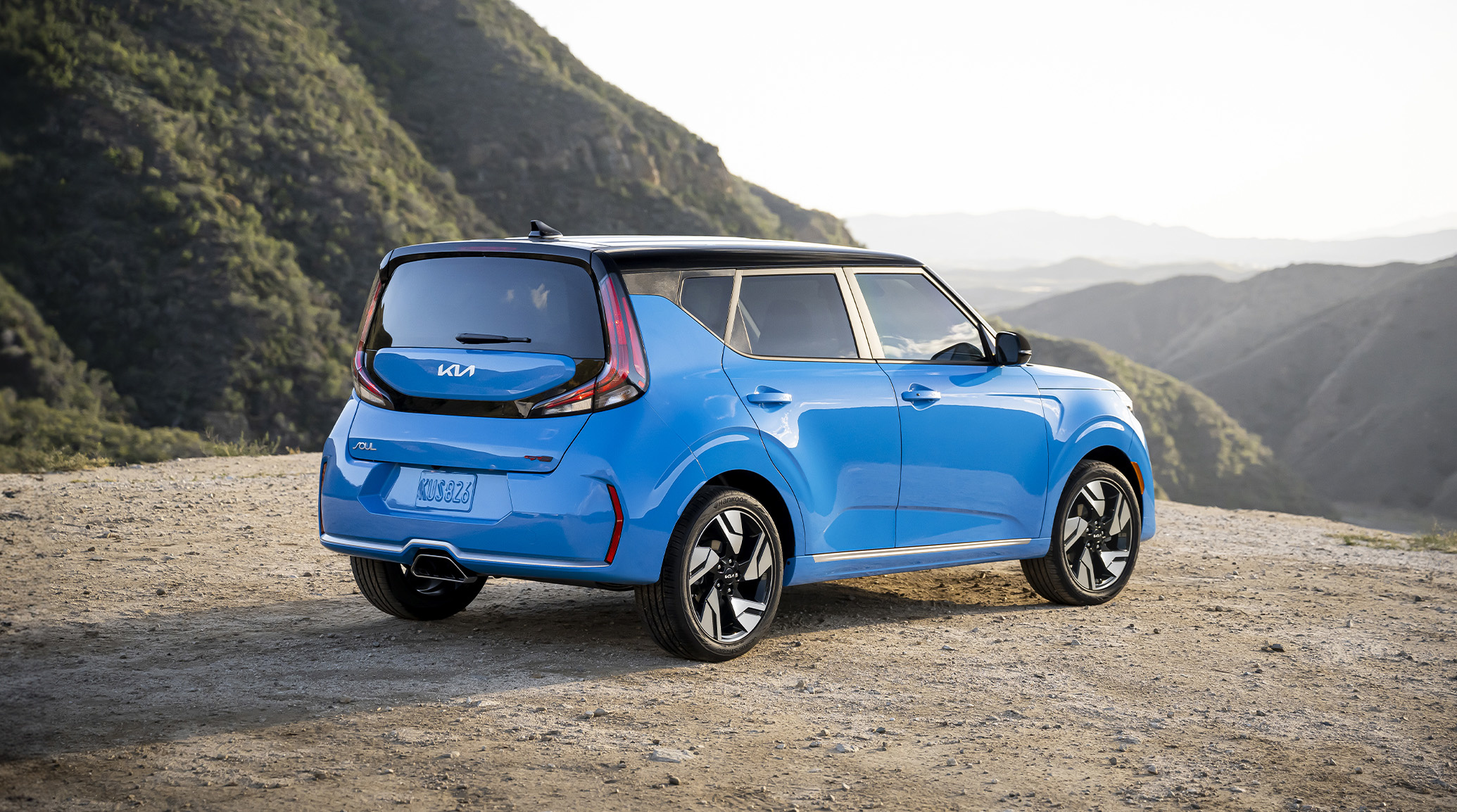 Blue Kia Soul parked on a scenic mountain overlook, showcasing its distinctive hatchback design