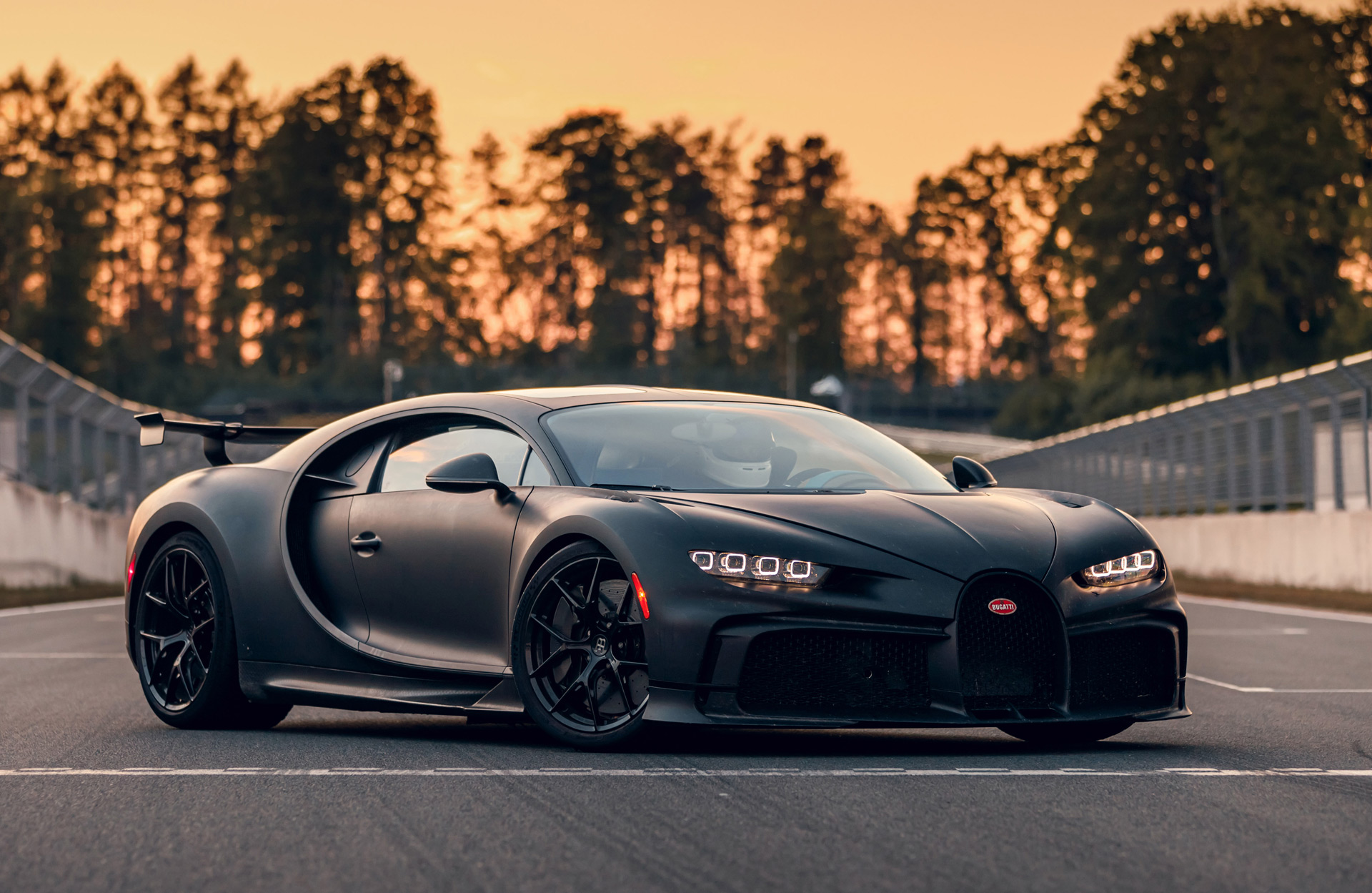 Bugatti Chiron positioned on a racetrack during sunset, showcasing its aggressive performance-focused design