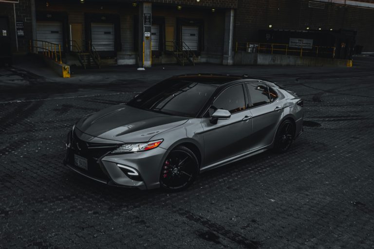 A Camry in black is stanidng on a concrete patch