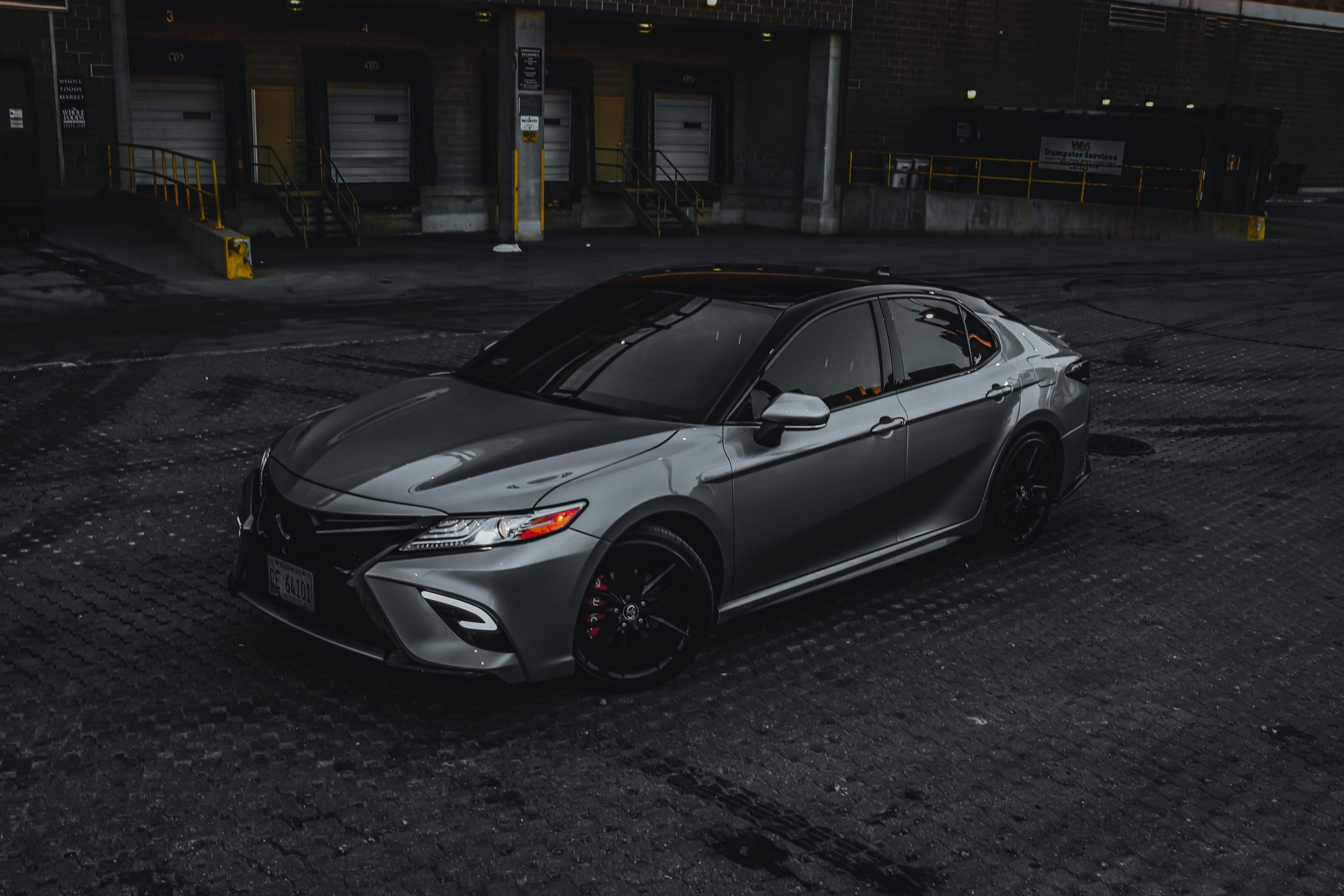 A Camry in black is stanidng on a concrete patch