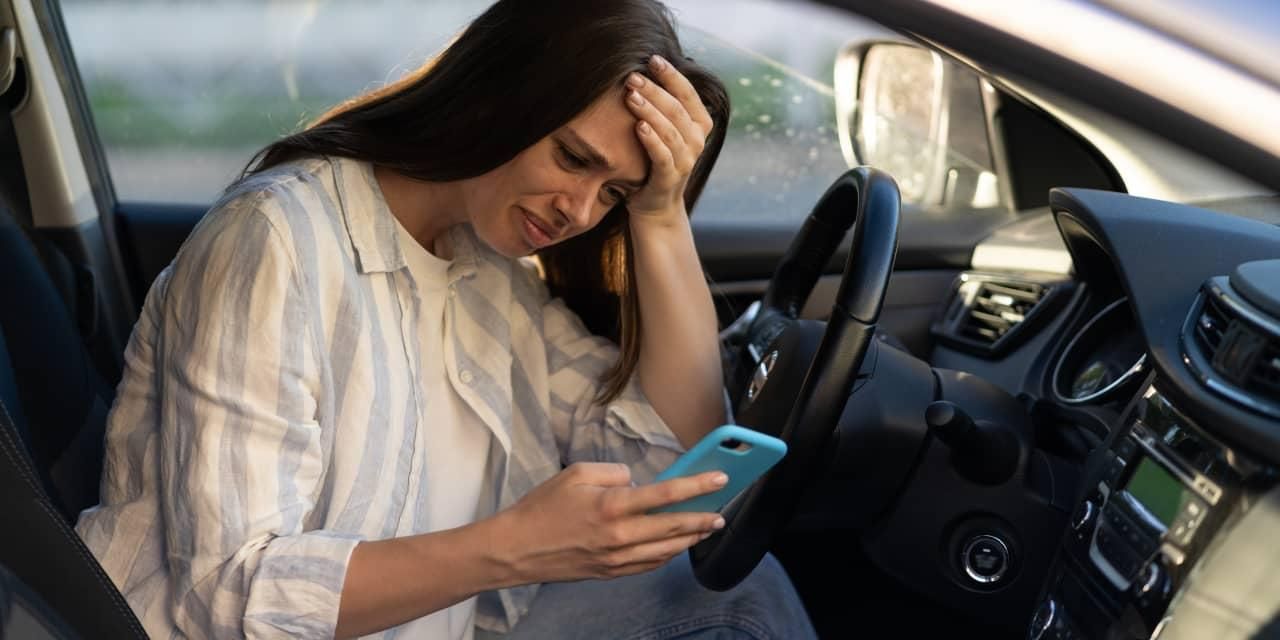 Worried woman checking her phone inside car