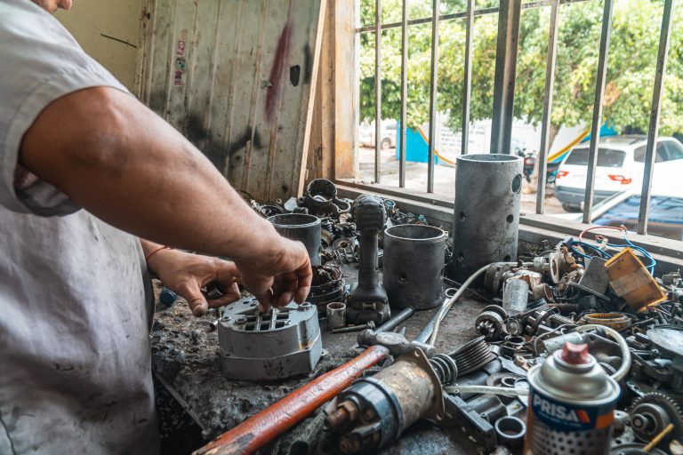 A man is cleaning the car parts after removing them from the engine