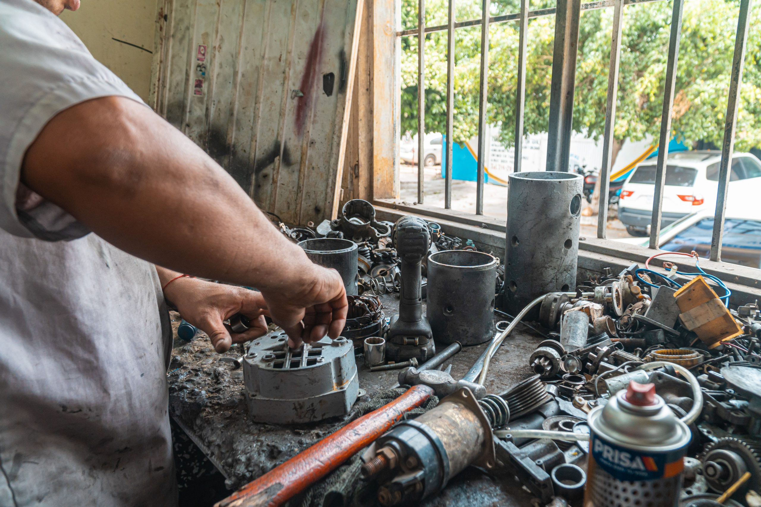 A man is cleaning the car parts after removing them from the engine