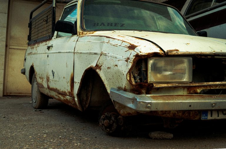 An old rusty car is standing in a closed garage