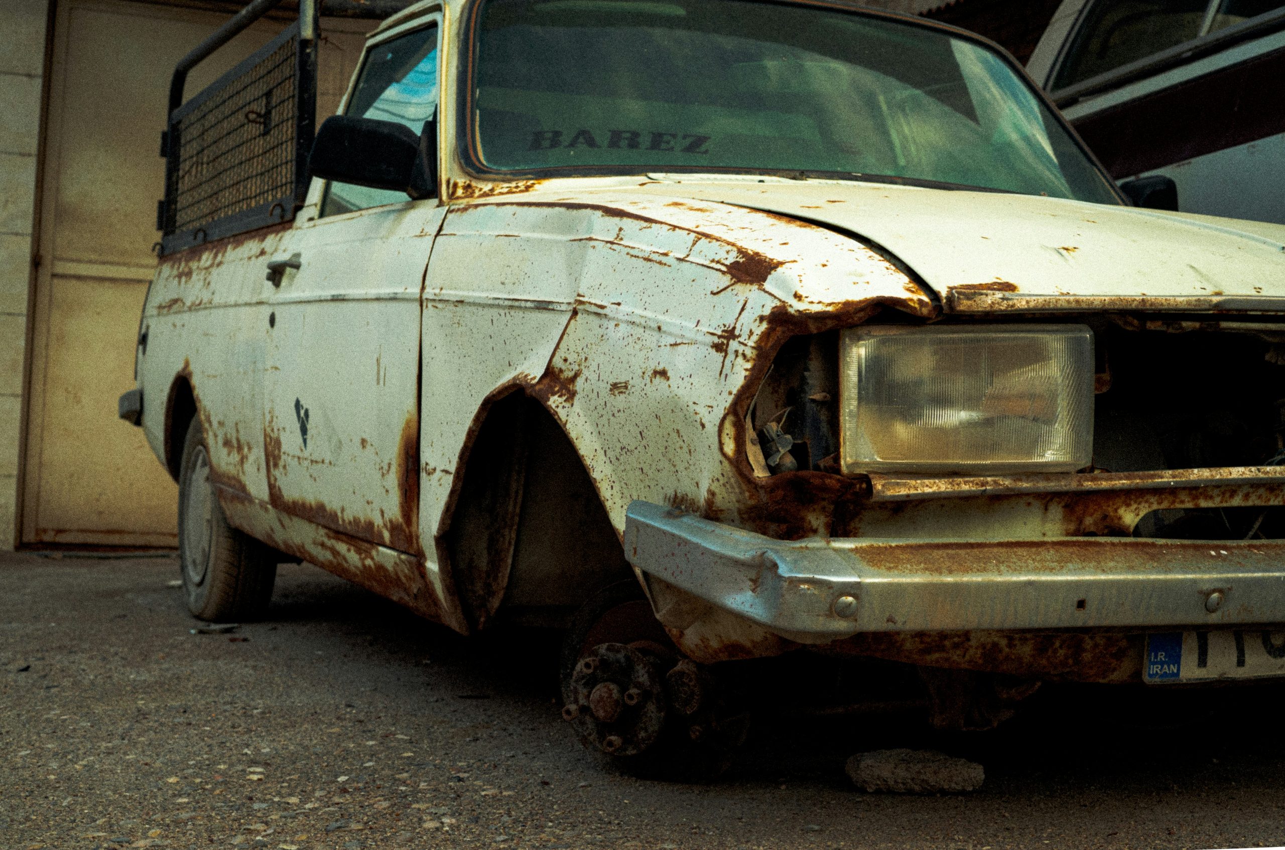 An old rusty car is standing in a closed garage