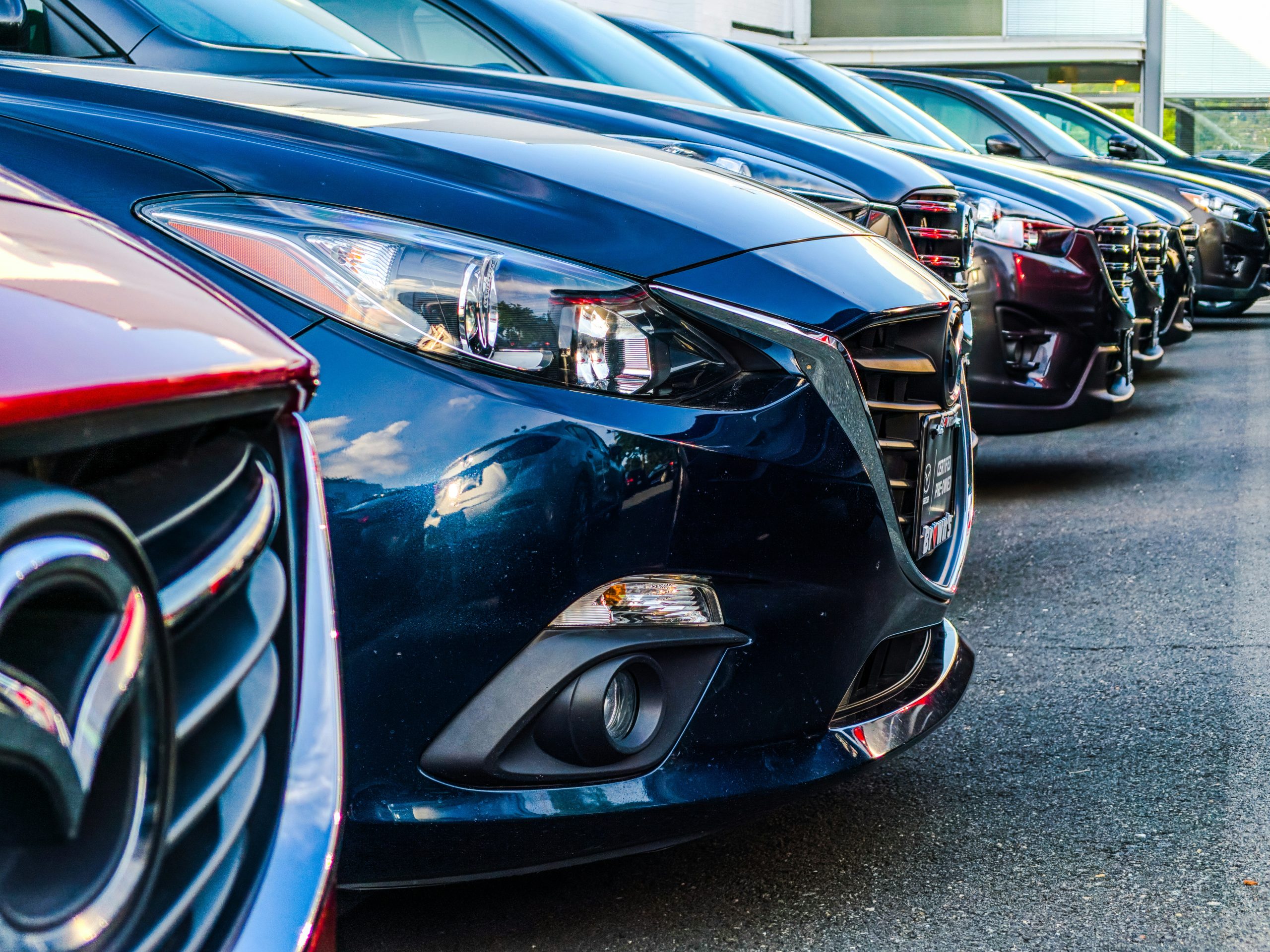 Many cars of different brands are standing in a dealership parking