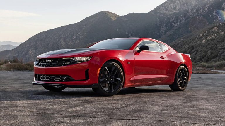 Chevrolet Camaro parked against a dramatic mountain backdrop on an open roadway