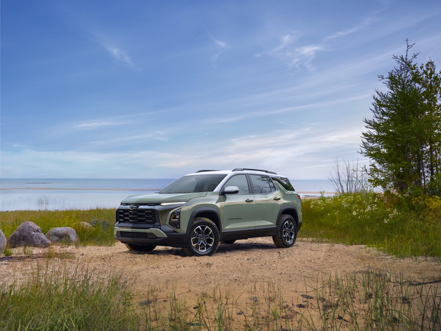 Chevrolet Equinox parked beside a lakeshore with trees and mountains nearby