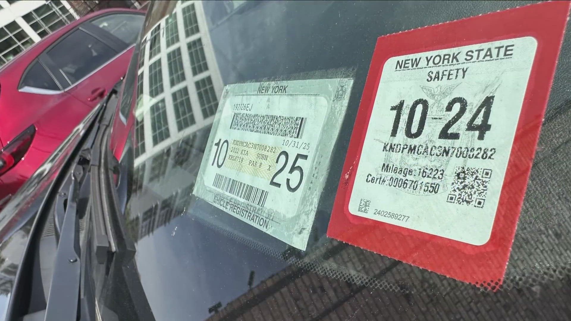 Close-up of New York vehicle registration and safety inspection stickers displayed on a car windshield