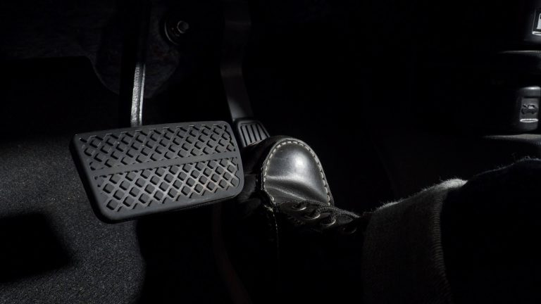 Close-up of a driver’s foot pressing the brake pedal inside a dark car interior