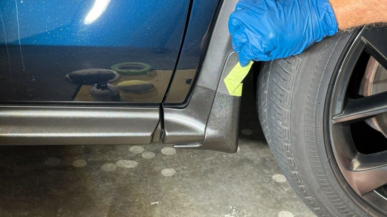 Close-up of a vehicle’s lower body trim and wheel area during exterior inspection