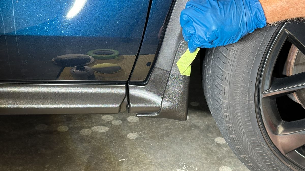 Close-up of a vehicle’s lower body trim and wheel area during exterior inspection