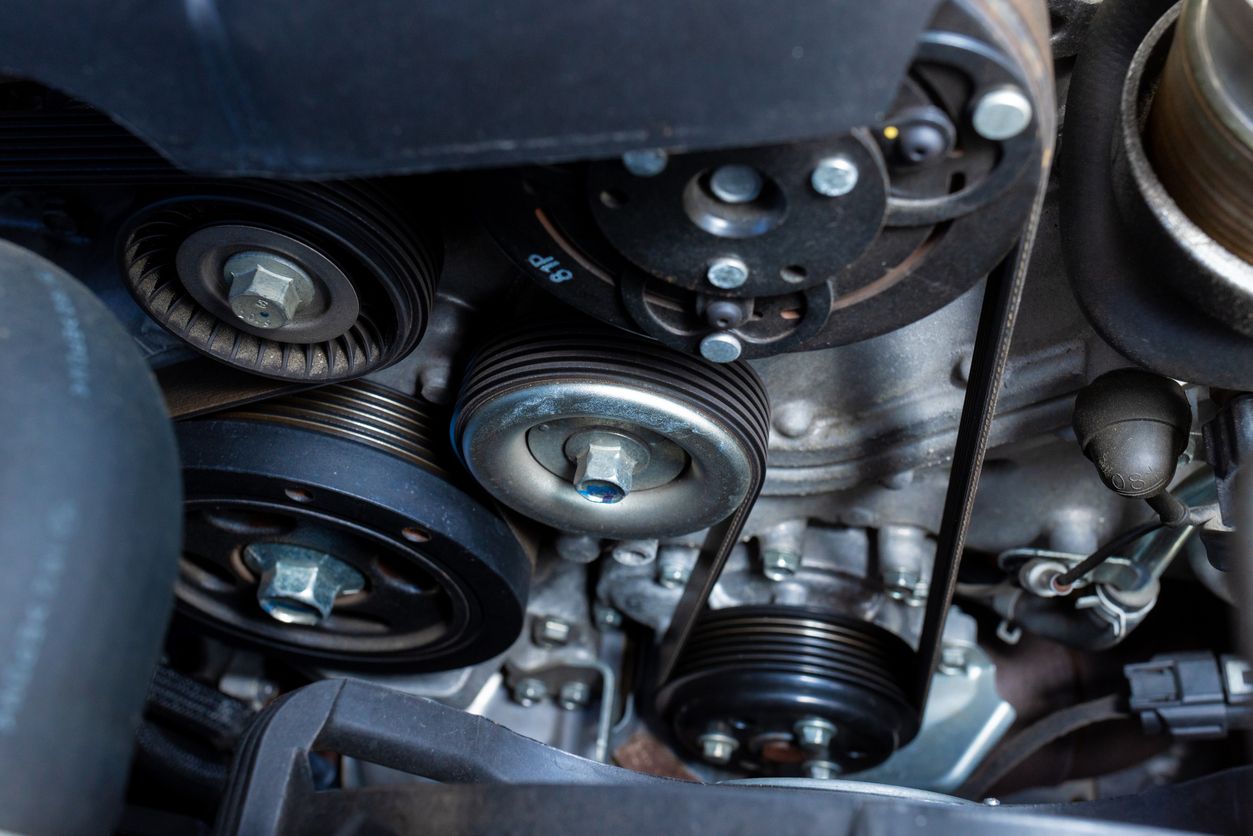 Close-up of an engine’s serpentine belt, pulleys, and accessory drive components during maintenance
