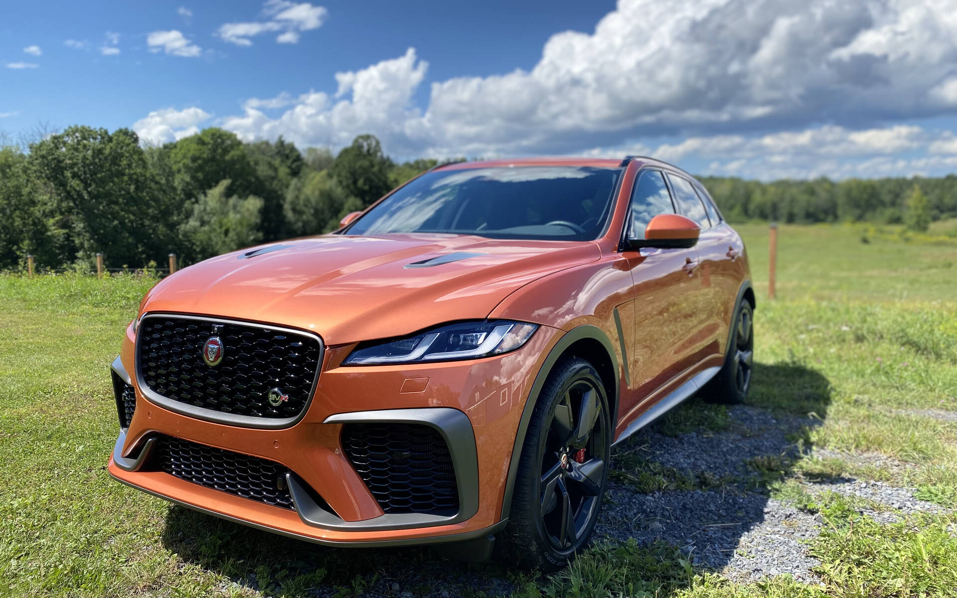 Copper-orange Jaguar F-Pace SVR parked on grass, showcasing its sporty front styling