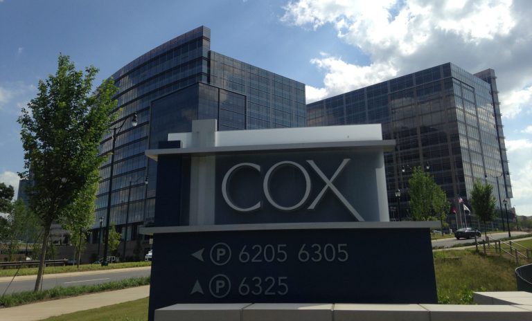 Cox Automotive headquarters sign displayed outside modern glass office buildings on a sunny day