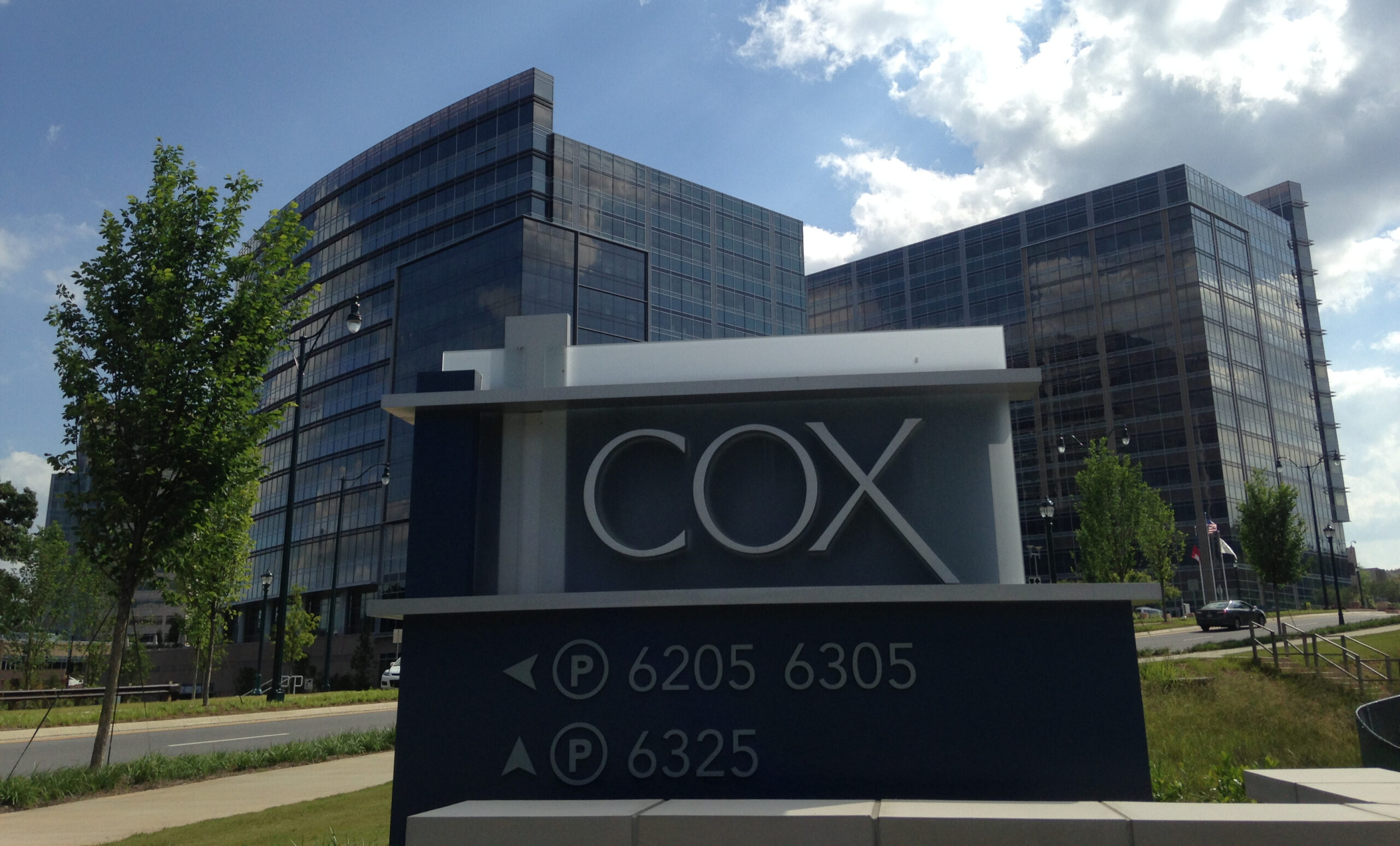Cox Automotive headquarters sign displayed outside modern glass office buildings on a sunny day