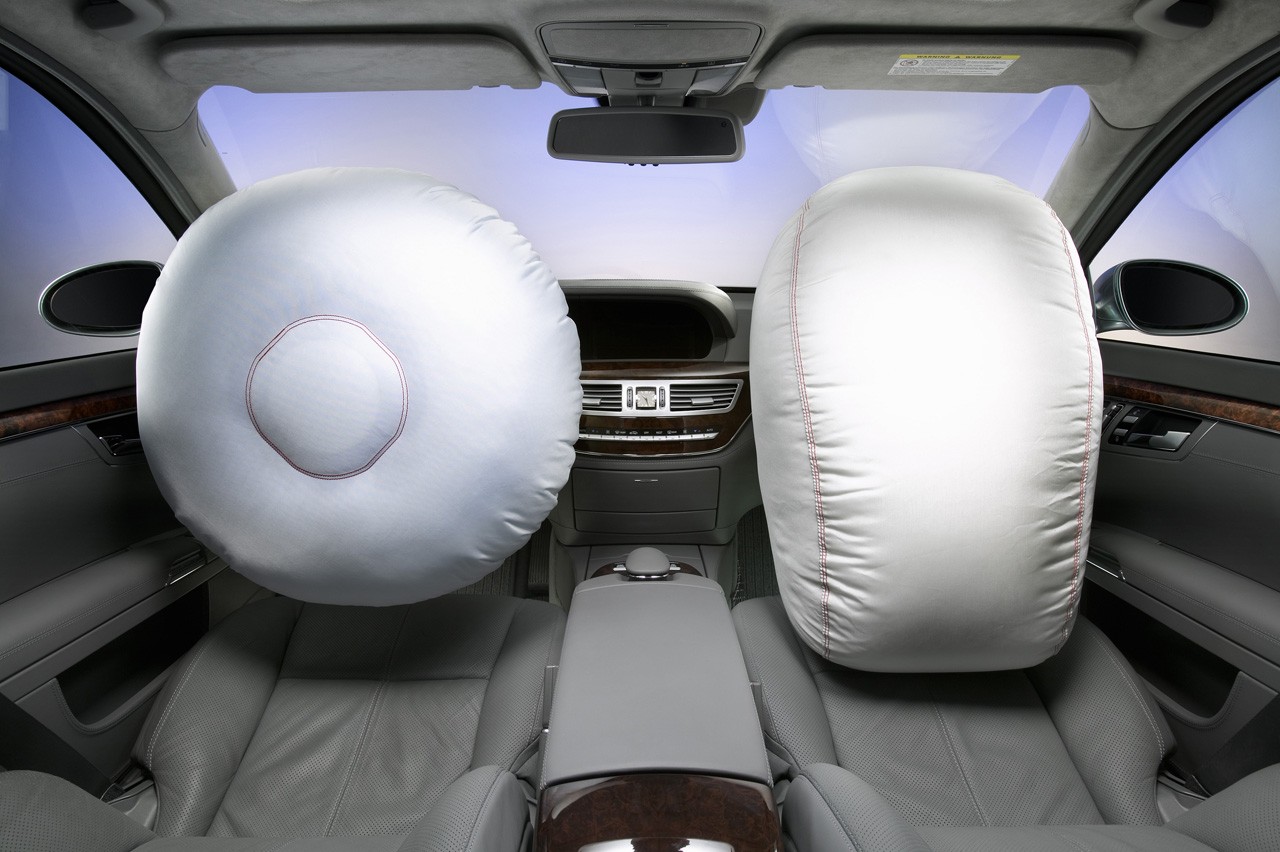 Deployed front airbags inside a luxury sedan demonstrate occupant protection during a frontal collision
