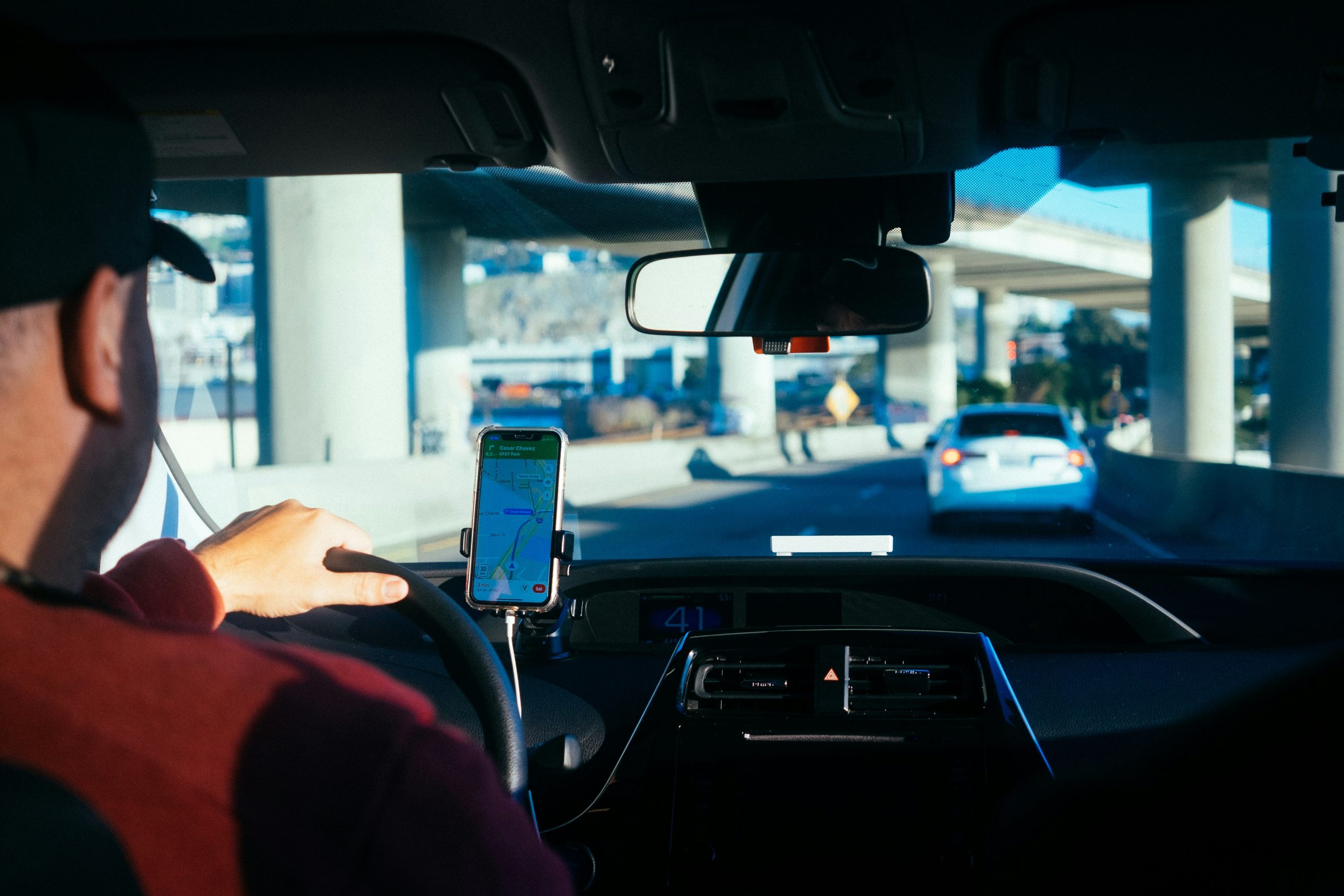 Internal of a car is shown with a mobile stand and a driver is driving his car