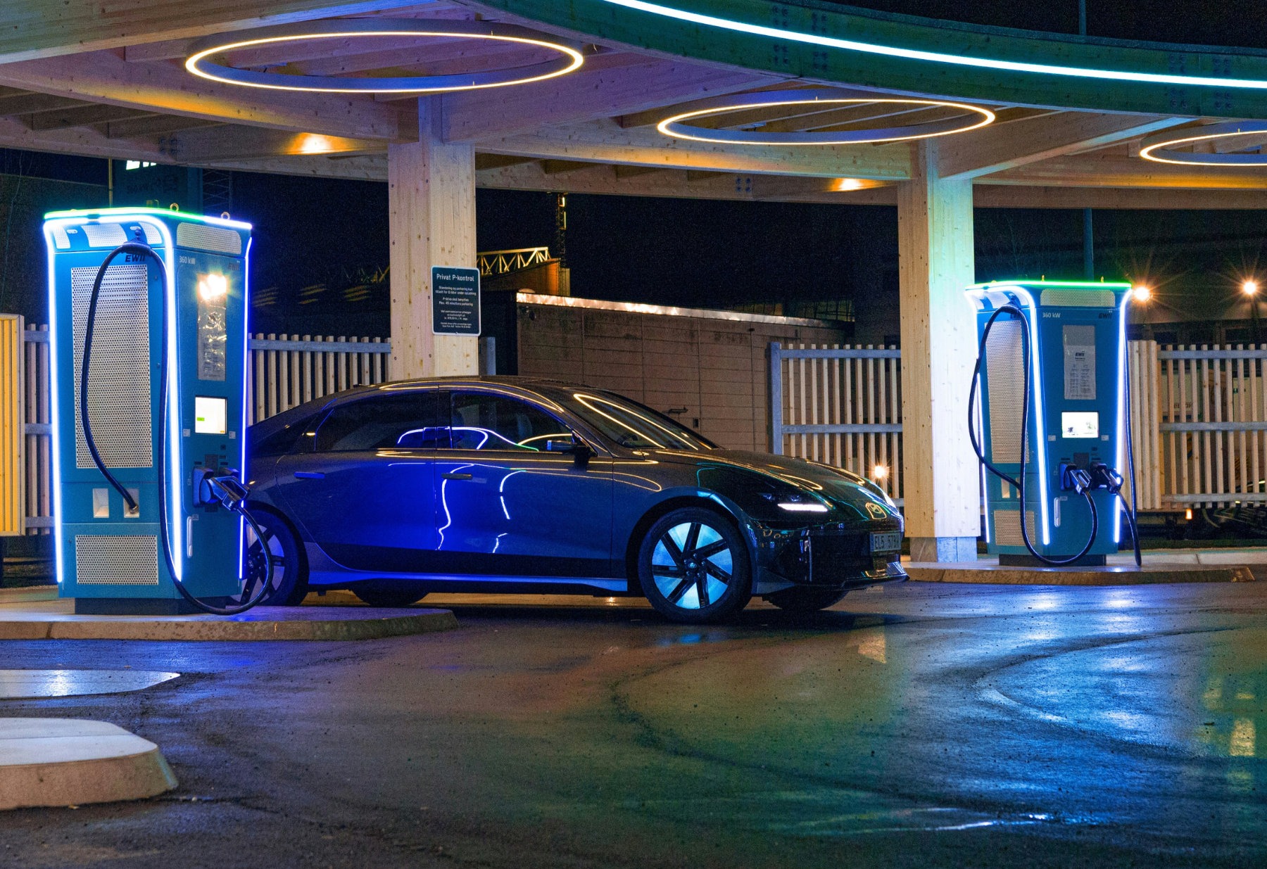 electric vehicle plugged into a modern public charging station at night