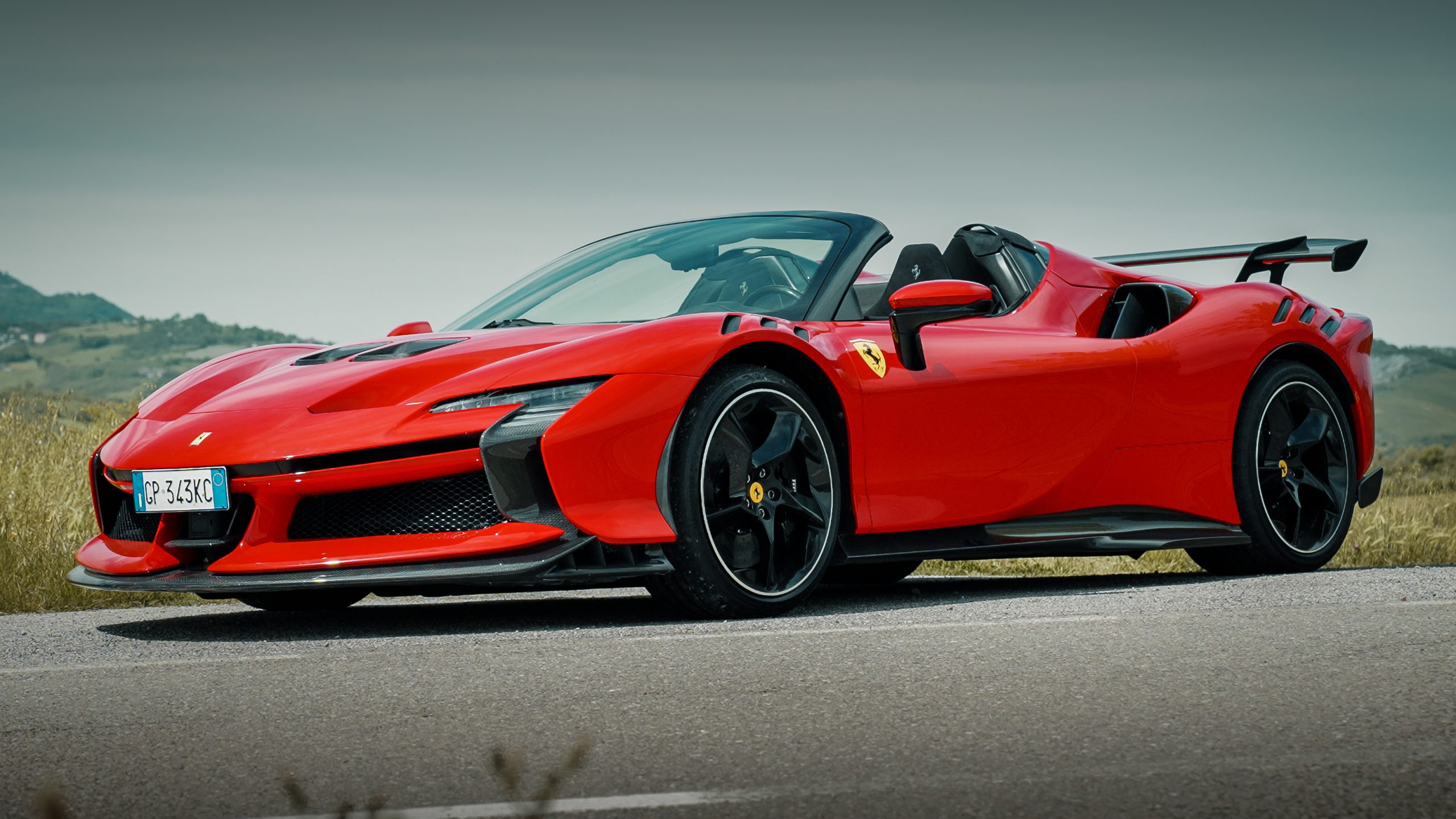 Ferrari SF90 Spider parked on a scenic mountain road with an open-air cockpit