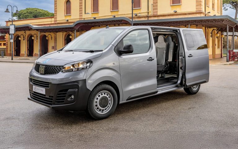 Fiat Scudo van parked outside a historic station, showcasing its spacious passenger access