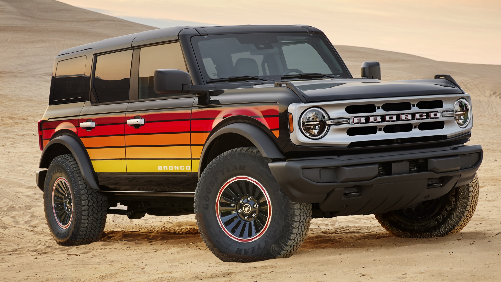 Ford Bronco parked on desert dunes, showcasing rugged off-road styling and capability