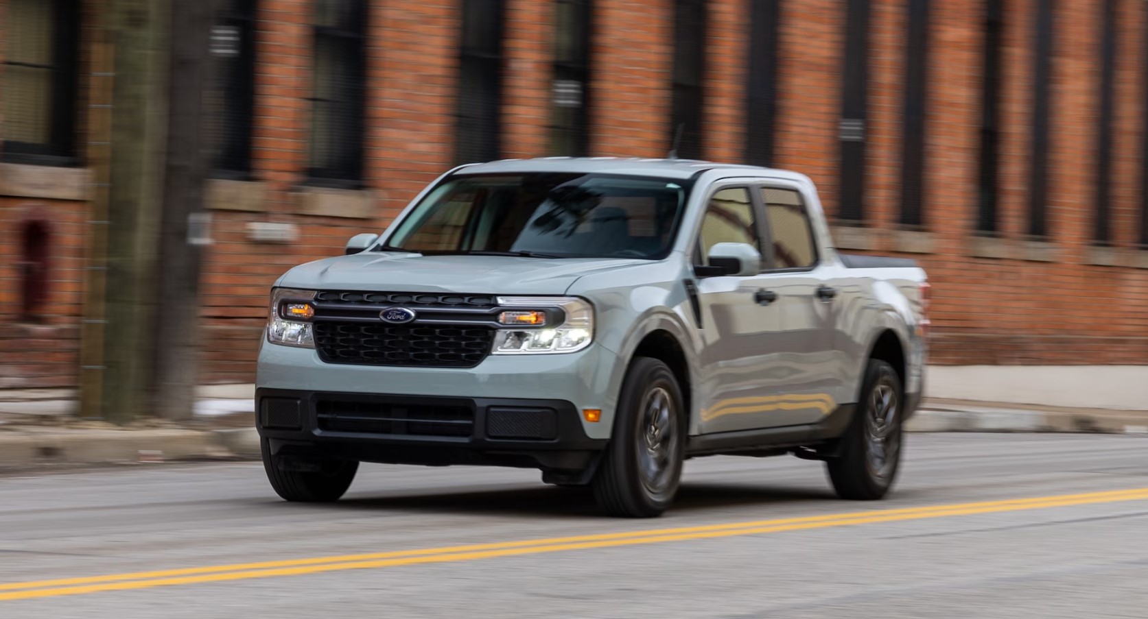 Ford Maverick Hybrid drives through an urban street, showcasing its compact pickup design and practicality