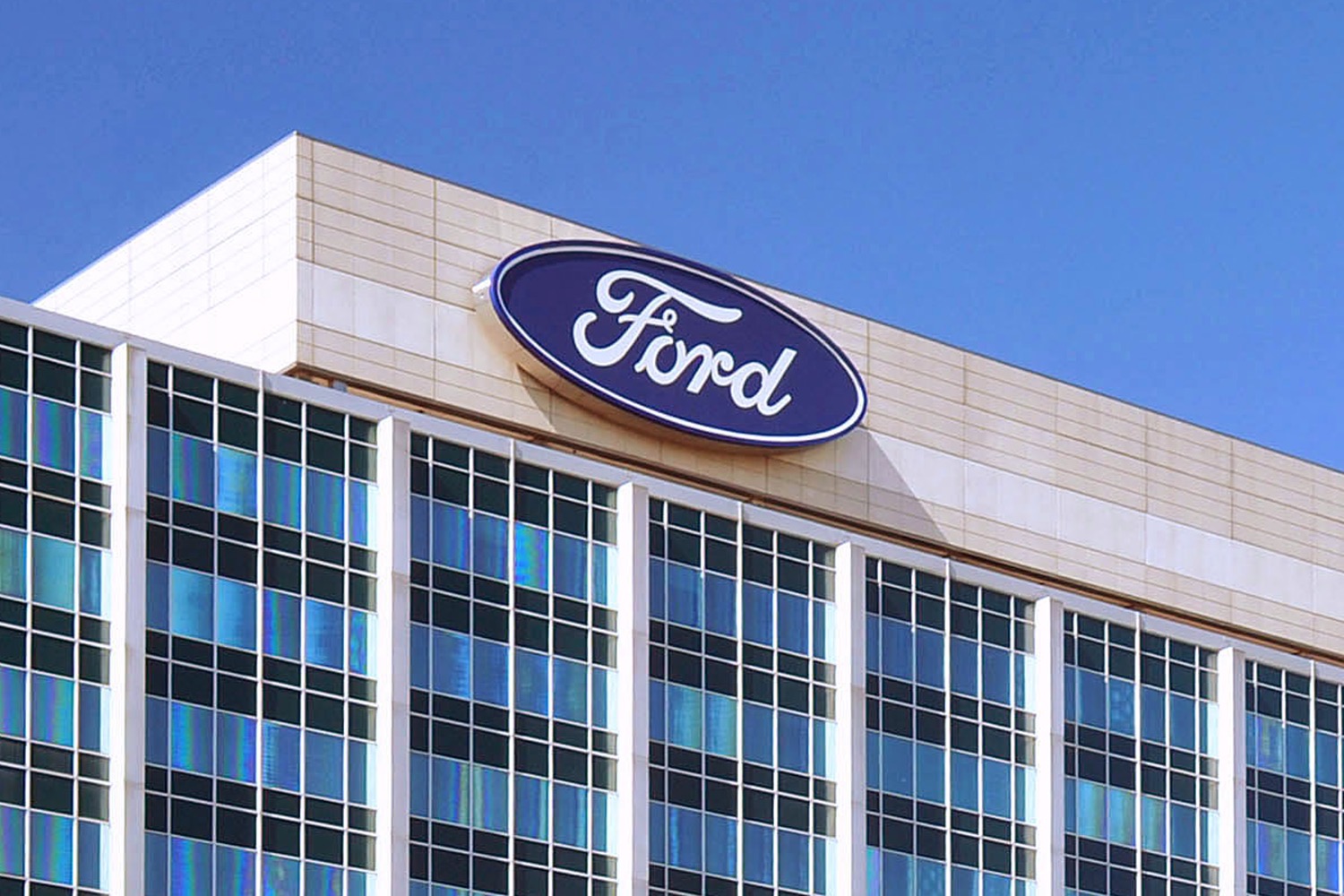 Ford headquarters building featuring the iconic blue oval logo under clear skies