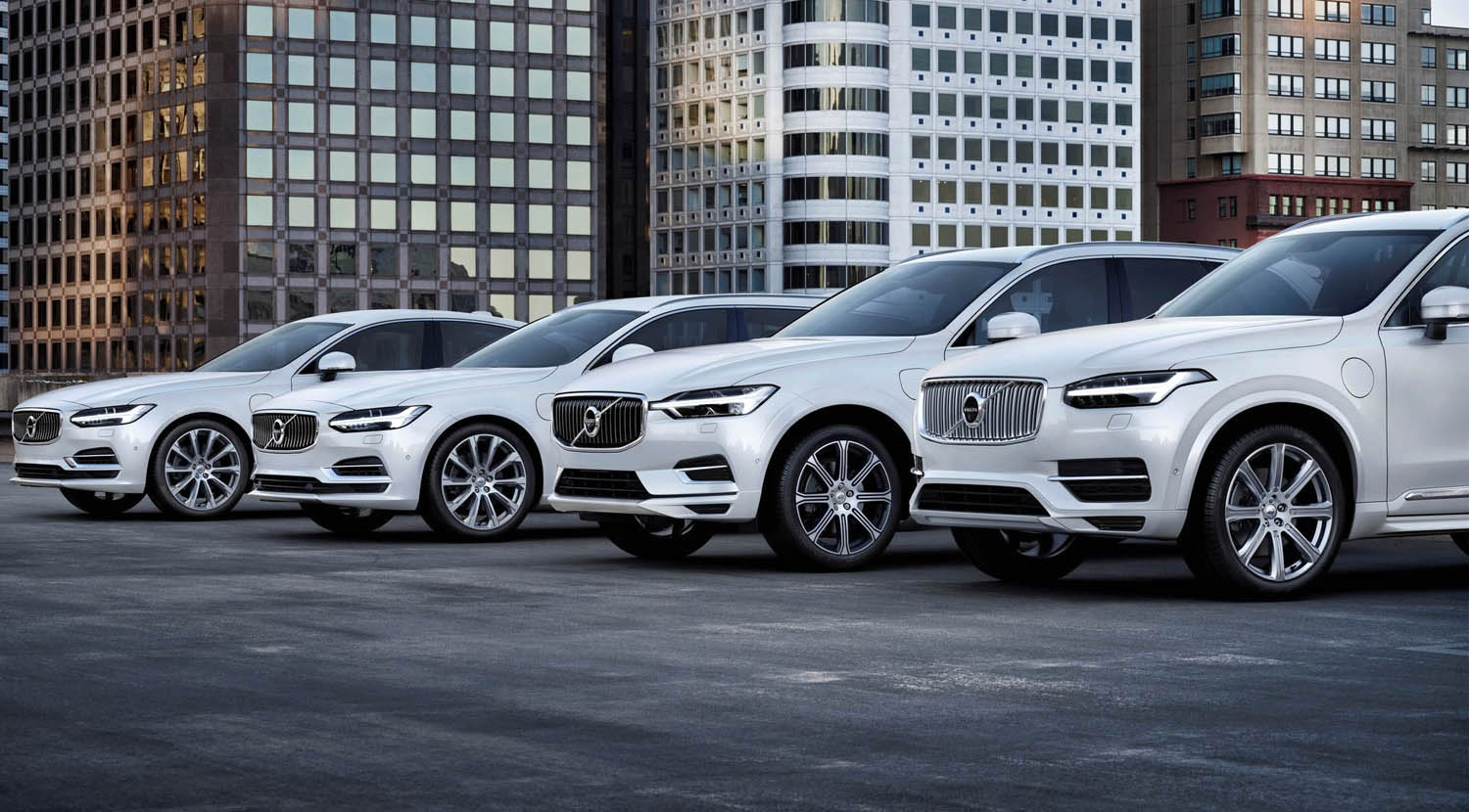 Four Volvo SUVs lined up on a city street with modern buildings behind