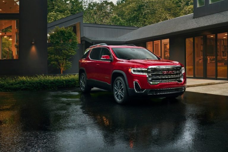 GMC Acadia parked outside a modern home at dusk, highlighting its upscale SUV styling