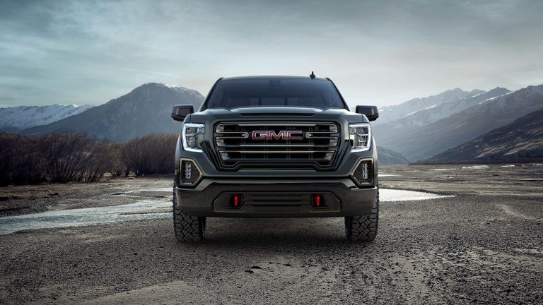GMC pickup faces forward against a dramatic alpine backdrop, highlighting its rugged design and stance